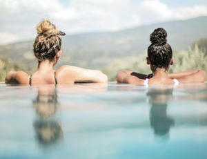 Zwei Frauen genießen die Aussicht in einem Infinity Pool