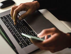 Mensch arbeitet an Notebook und Smartphone