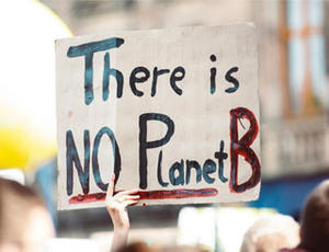 Demonstrant hält Plakat mit der Aufschrift "There is no Planet B"