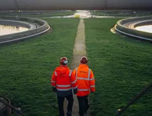 Zwei Veolia-Ingenieure auf einer Wiese mit Klärwasserbecken