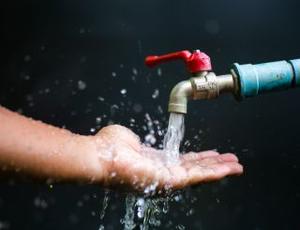 Reines Wasser läuft aus einem Wasserhahn auf eine Hand
