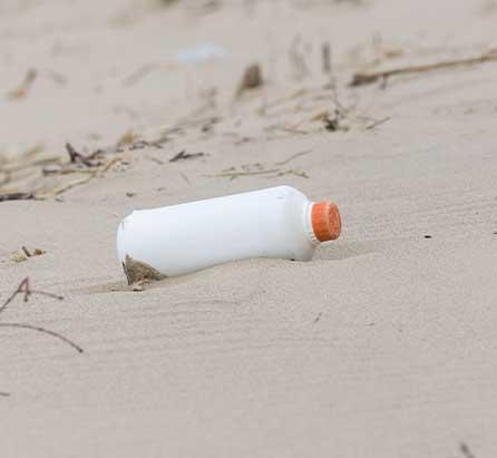 Eine weiße Plastikflasche verschmutzt den Strand