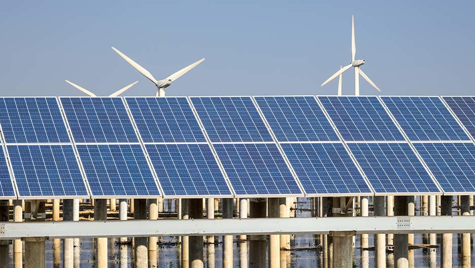 Solarzellen mit Windkrafträdern im Hintergrund