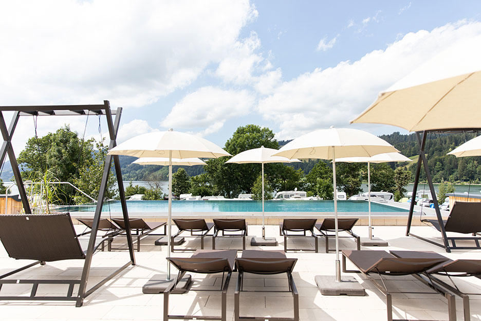 Der Alpsee Camping Infinity Pool mit Liegen und Sonnenschirmen davor