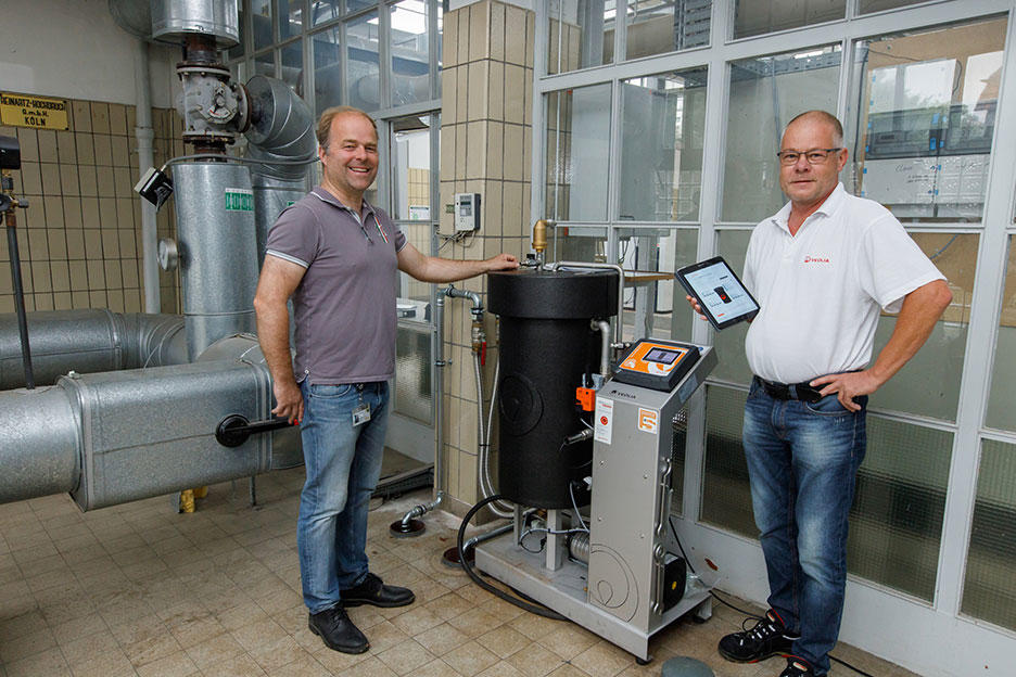 Tobias Broxtermann von EWE links und Veolia-Experte Arne Gebken rechts vor der BerkeSELECT Heizwasseranlage | Quelle Veolia | Fotograf Andreas Burmann