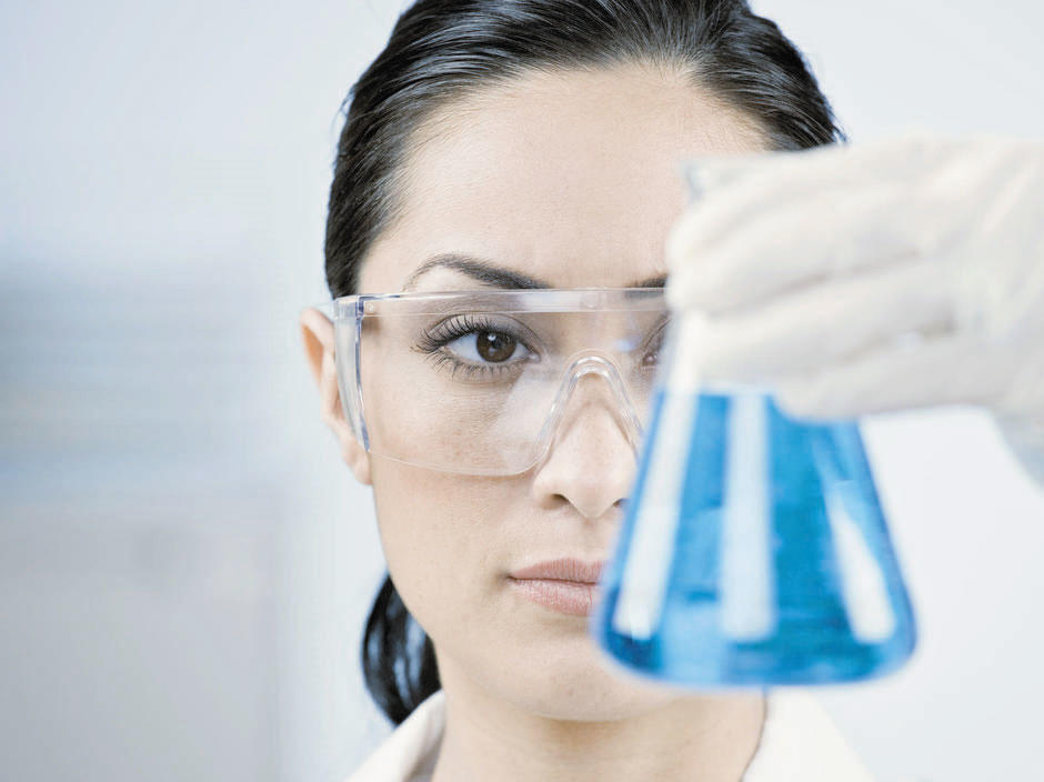 Laborantin hält Laborglas mit blauer Flüssigkeit 