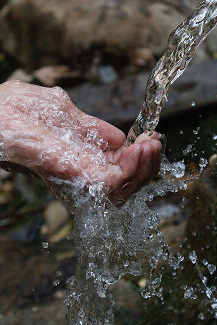 Hand unter einem Wasserstrahl. Foto von Samad Deldar